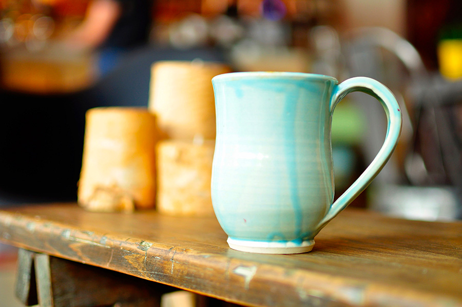 Ceramic mug with teal glaze on a wooden shop table